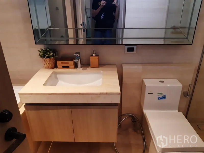 Condominium for rent in Watthana, Bangkok - Bathroom with vanity, wide mirror and toilet.