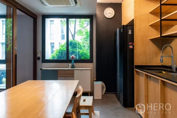 Townhouse for rent in Lat Phrao, Bangkok - Bright kitchen with large window, black refrigerator and sink.