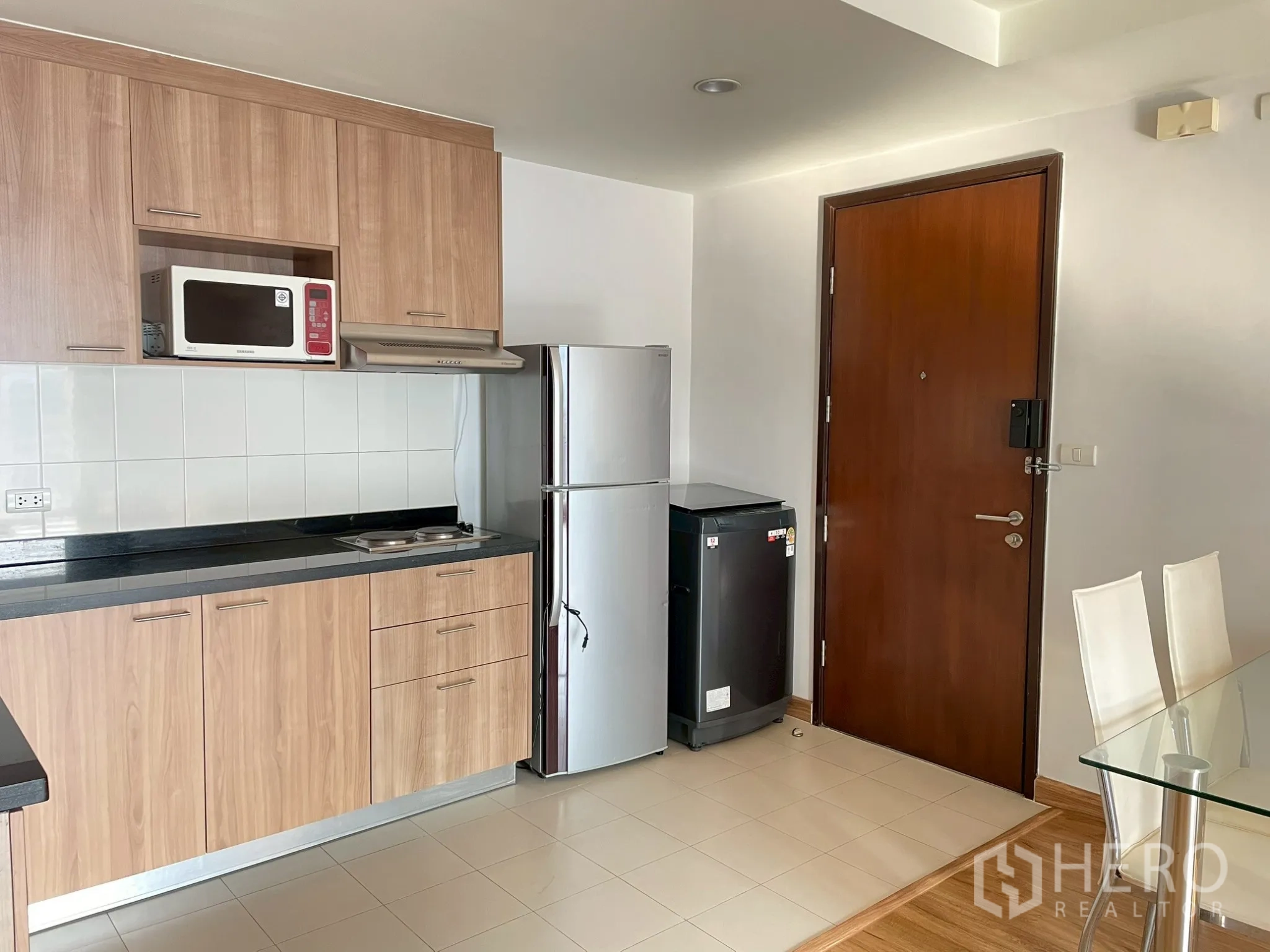อพาร์ทเมนท์ for rent in Khlong Toei, Bangkok - มุมครัวแสดงตู้ ซิงก์ เตา เครื่องดูดควัน ตู้เย็น และประตูทางเข้า
