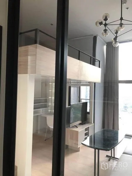 公寓 出售在Ratchathewi, Bangkok - 挑高客厅带阁楼、电视柜与餐桌。