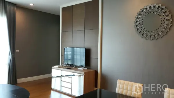 Condominium for rent in Khlong Toei, Bangkok - Living room with feature TV wall, console cabinet and large curtained window.