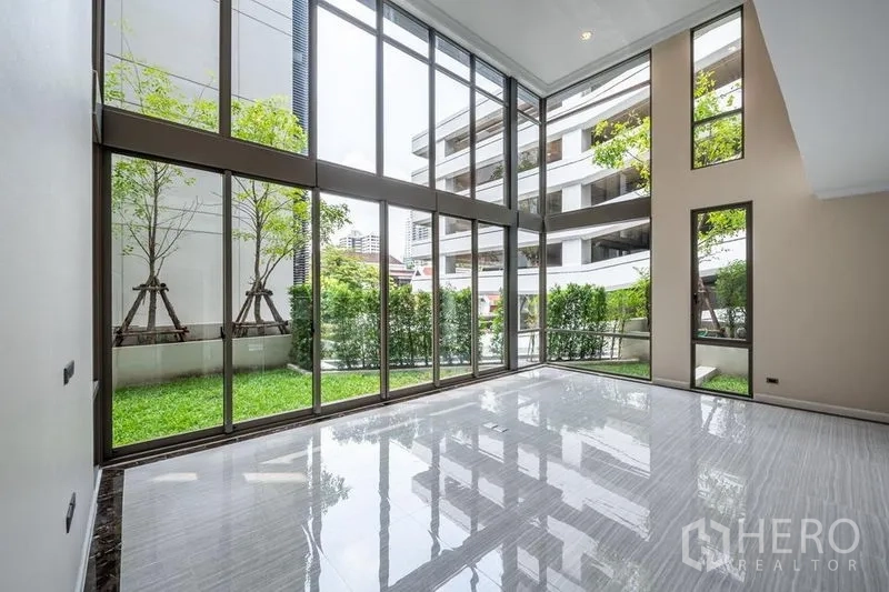 联排别墅 出租在Khlong Toei, Bangkok - 双层挑高客厅，整面落地玻璃连接私家花园