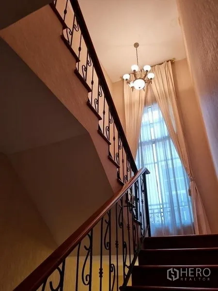 Detached House for rent in Yan Nawa, Bangkok - Stairwell with wrought-iron railing, chandelier and tall window bringing in natural light.