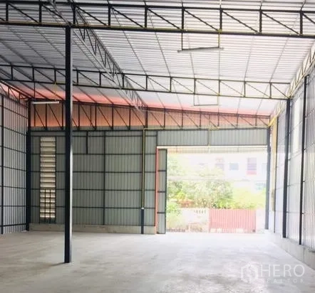Warehouse for rent in Bueng Kum, Bangkok - Bright warehouse interior with a high steel-truss roof, polished concrete floor, and a wide loading door allowing natural light.