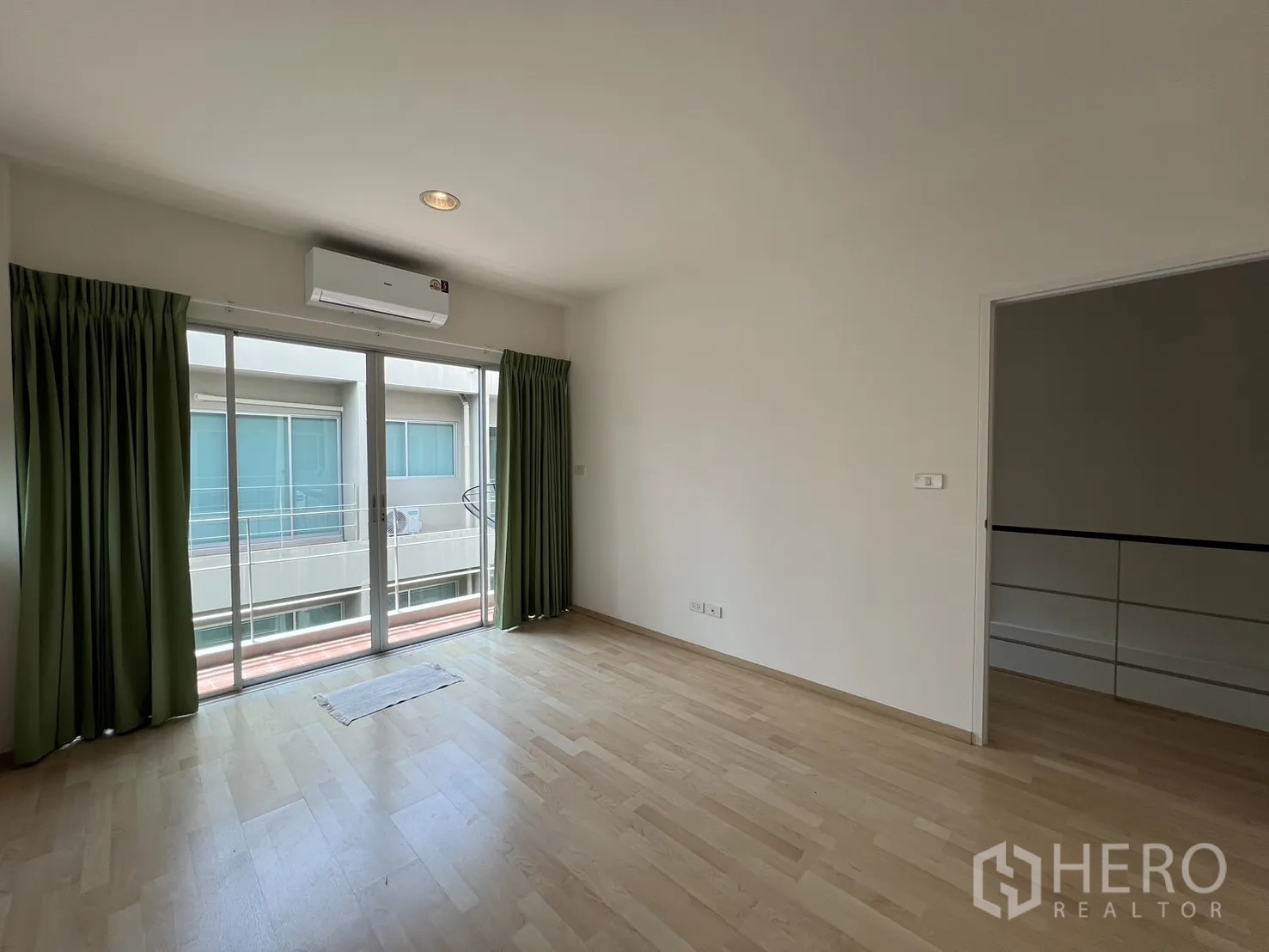 Townhouse for rent in Suan Luang, Bangkok - Bedroom with bed, TV stand, shelves, and leafy views outside.