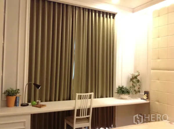 公寓 出租在Watthana, Bangkok - 卧室工作区配长条内置书桌、椅子、绿植与落地遮光窗帘。