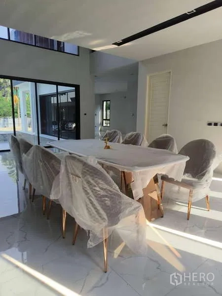 Detached House for rent in Phra Khanong, Bangkok - Alternate view of the dining area with a long table and sliding glass doors.