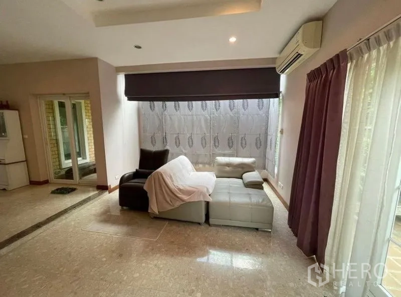Detached House for rent - Cozy living corner with L-shaped sofa, large windows with curtains, and sliding glass doors.