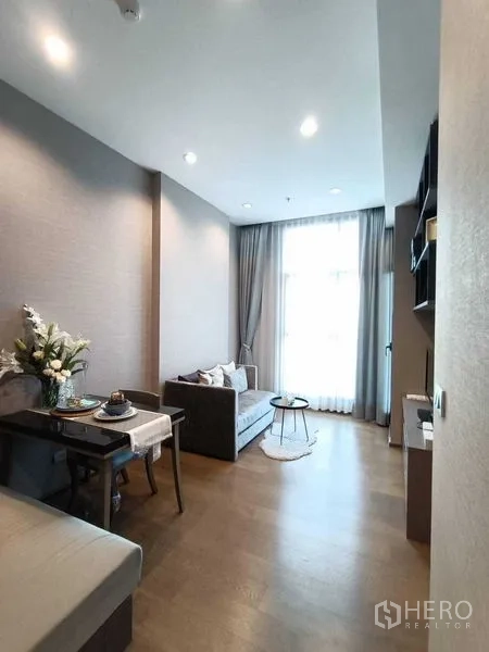 Condominium for rent or sale in Bang Rak, Bangkok - Bright living and dining area with sofa, small table and floor-to-ceiling window.