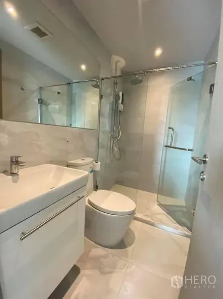 公寓 出租在Watthana, Bangkok - 现代浴室，玻璃淋浴间、洗手台与马桶，浅色瓷砖。