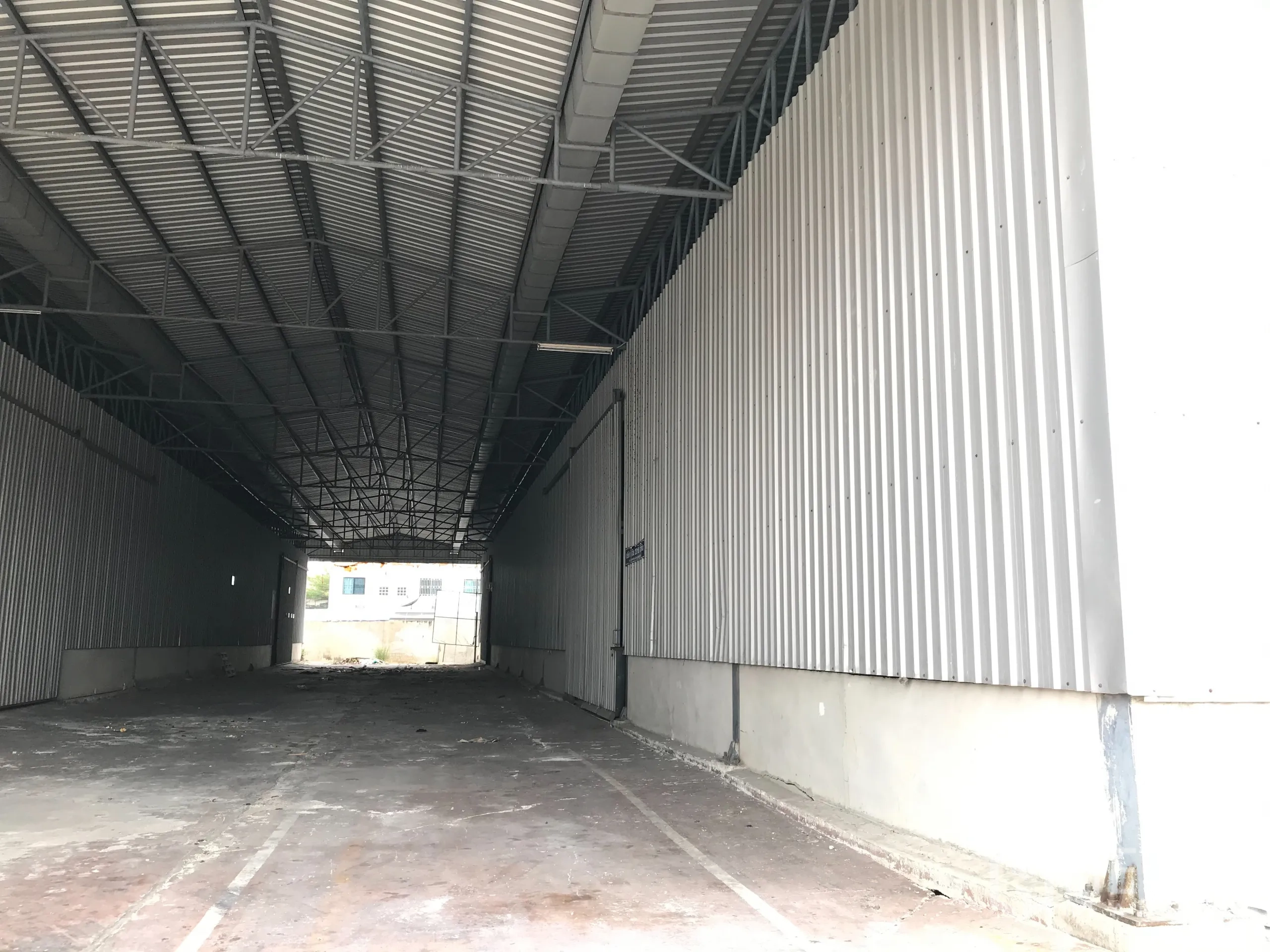 Warehouse for rent in Mueang Samut Prakan, Samut Prakan - Covered loading bay with metal cladding and tall roof suitable for truck access.