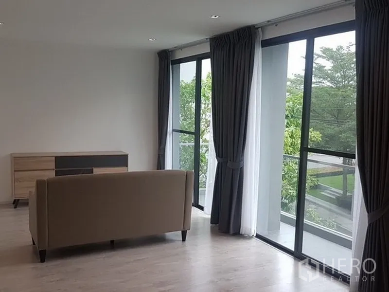 บ้าน ให้เช่าในPrawet, Bangkok - ห้องนั่งเล่นครอบครัวกว้าง โซฟาและประตูกระจกบานเลื่อน เปิดสู่ระเบียงวิวสวน.