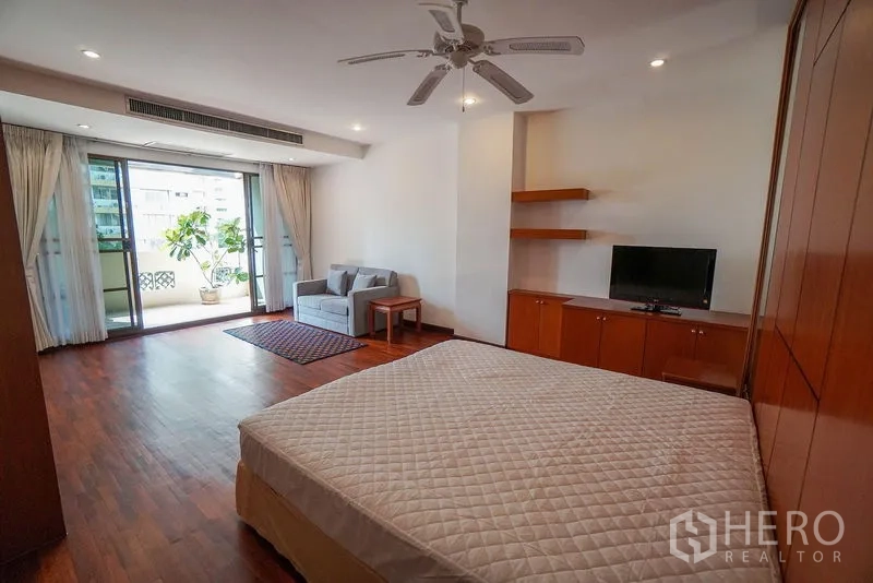 Apartment for rent in Watthana, Bangkok - Master bedroom angle showing balcony access and media cabinet.