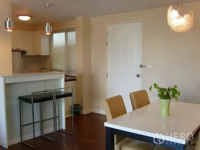 Condominium for rent in Watthana, Bangkok - Dining table beside a breakfast bar with pendant lighting near the entry.