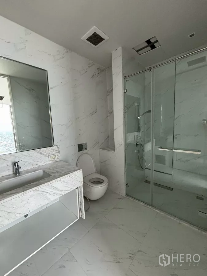 Condominium for sale in Bang Kho Laem, Bangkok - Marble-clad bathroom with walk-in glass shower, toilet and vanity.