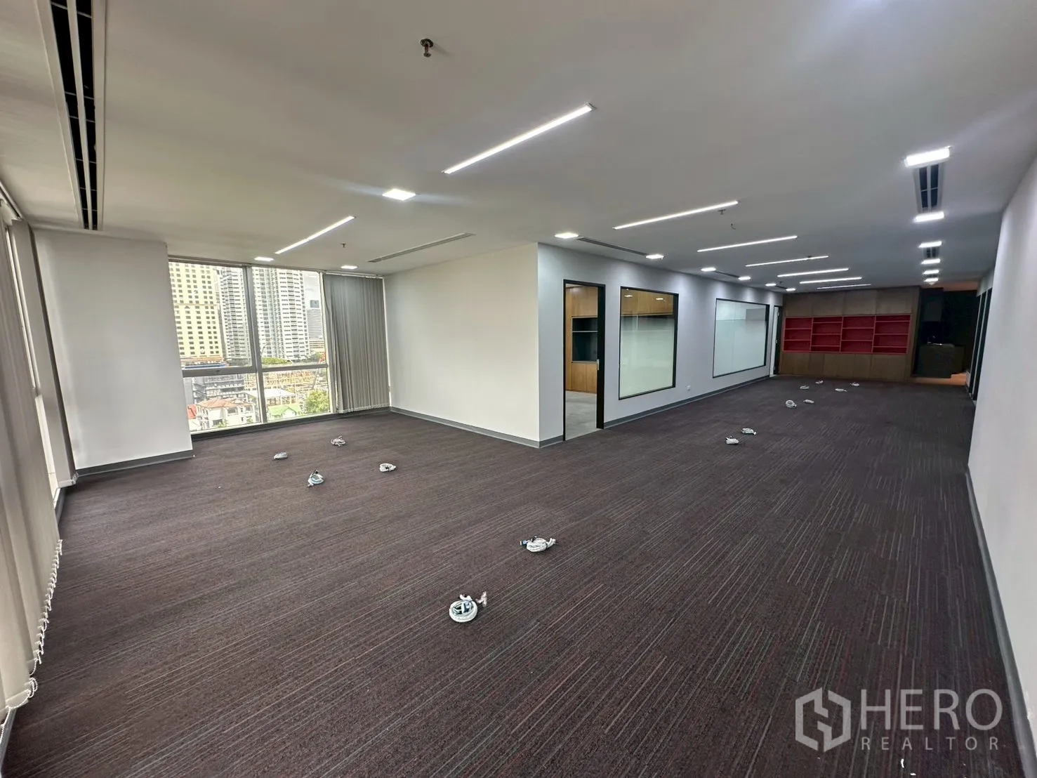 Office Space for rent - Open workspace with large city-view windows, carpet floors and interior glass panels.