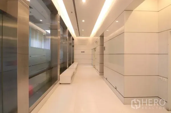 Office Space for rent in Bang Rak, Bangkok - Modern lift lobby with glass walls, stainless-steel finishes and built-in seating in a contemporary office building.