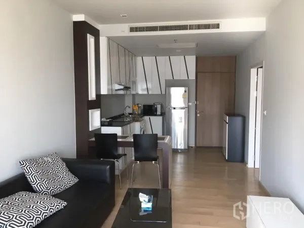 公寓 出租在Bangkok - 开放式起居与厨房，吧台餐位、沙发与自然木地板布局。