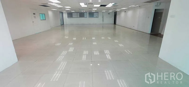 สำนักงาน ให้เช่าในHuai Khwang, Bangkok - ภาพมุมกลางของออฟฟิศว่าง พื้นกระเบื้อง ไฟฝังเพดาน และทางเข้าออกหลายด้าน.