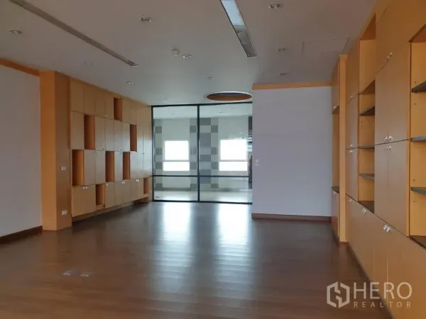 Office Space for rent in Khlong Toei, Bangkok - Open-plan office with wood flooring, extensive built-in cabinets and a glass-partitioned meeting room.