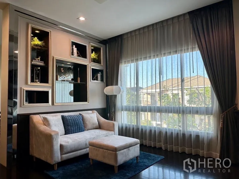 Detached House for rent - Bright sitting area with loveseat and ottoman beside a large window with sheer curtains.