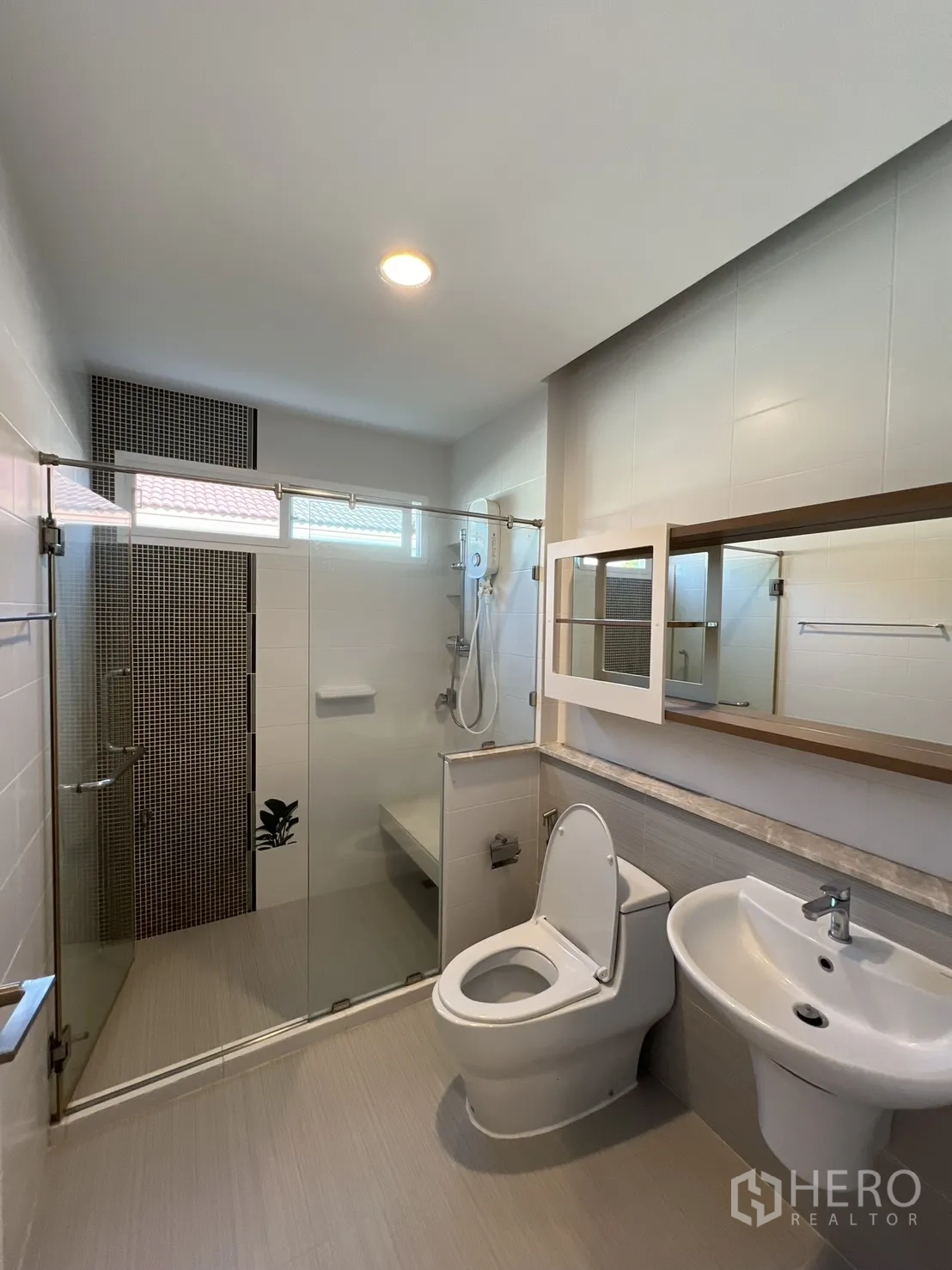 Detached House for rent in Bang Kapi, Bangkok - Modern bathroom featuring a glass-enclosed shower and large mirror.