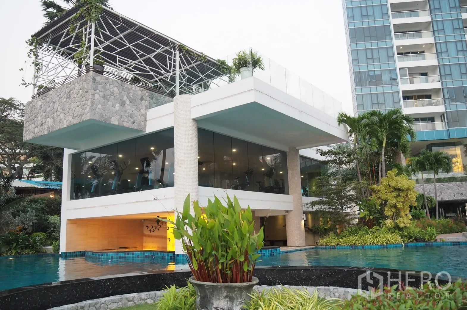 Condominium for rent in Bang Lamung, Chon Buri - Beachfront condominium facilities with a glass-walled gym above an infinity pool and lush gardens in Pattaya.