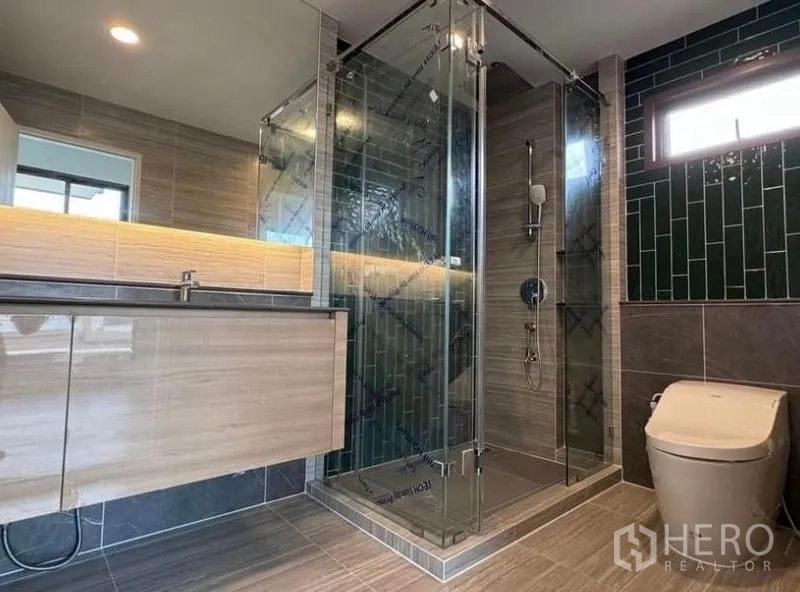 Detached House for rent in Bang Kapi, Bangkok - Contemporary bathroom with glass-enclosed shower, modern fittings and tiled walls.