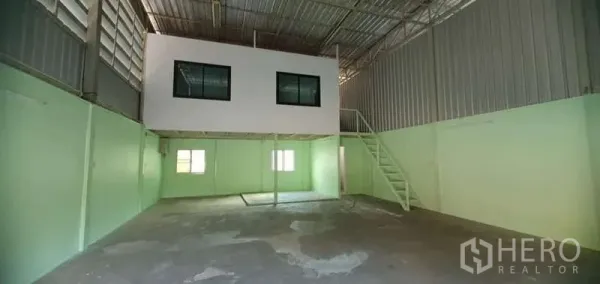 Warehouse for rent in Khlong Toei, Bangkok - Wide view of the warehouse floor with a white mezzanine office box and metal staircase under a steel roof.