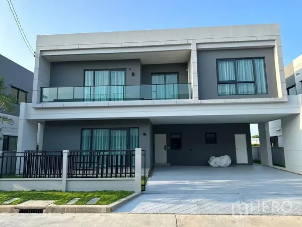 Detached House for rent in Bang Phli, Samut Prakan - Modern two-storey detached house exterior with glass balcony, gated front yard and covered carport in the Centro Bangna community.