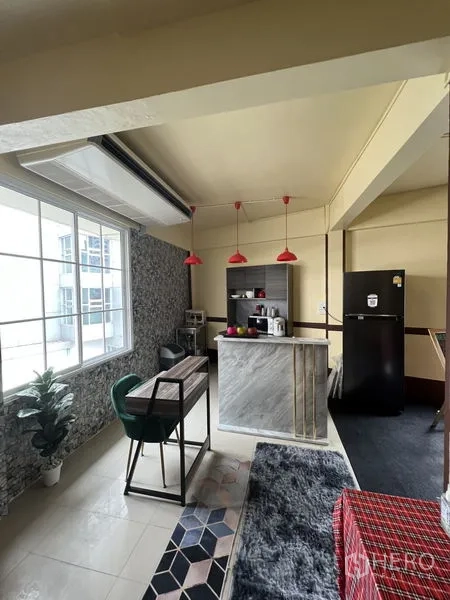 Shophouse for rent in Khlong Toei, Bangkok - Compact kitchenette with marble counter, red pendant lights, fridge and a work desk by a bright window.