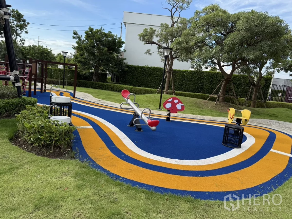 Townhouse for rent or sale in Bang Phli, Samut Prakan - Colorful playground with rubber surface, seesaw and slide in a garden.