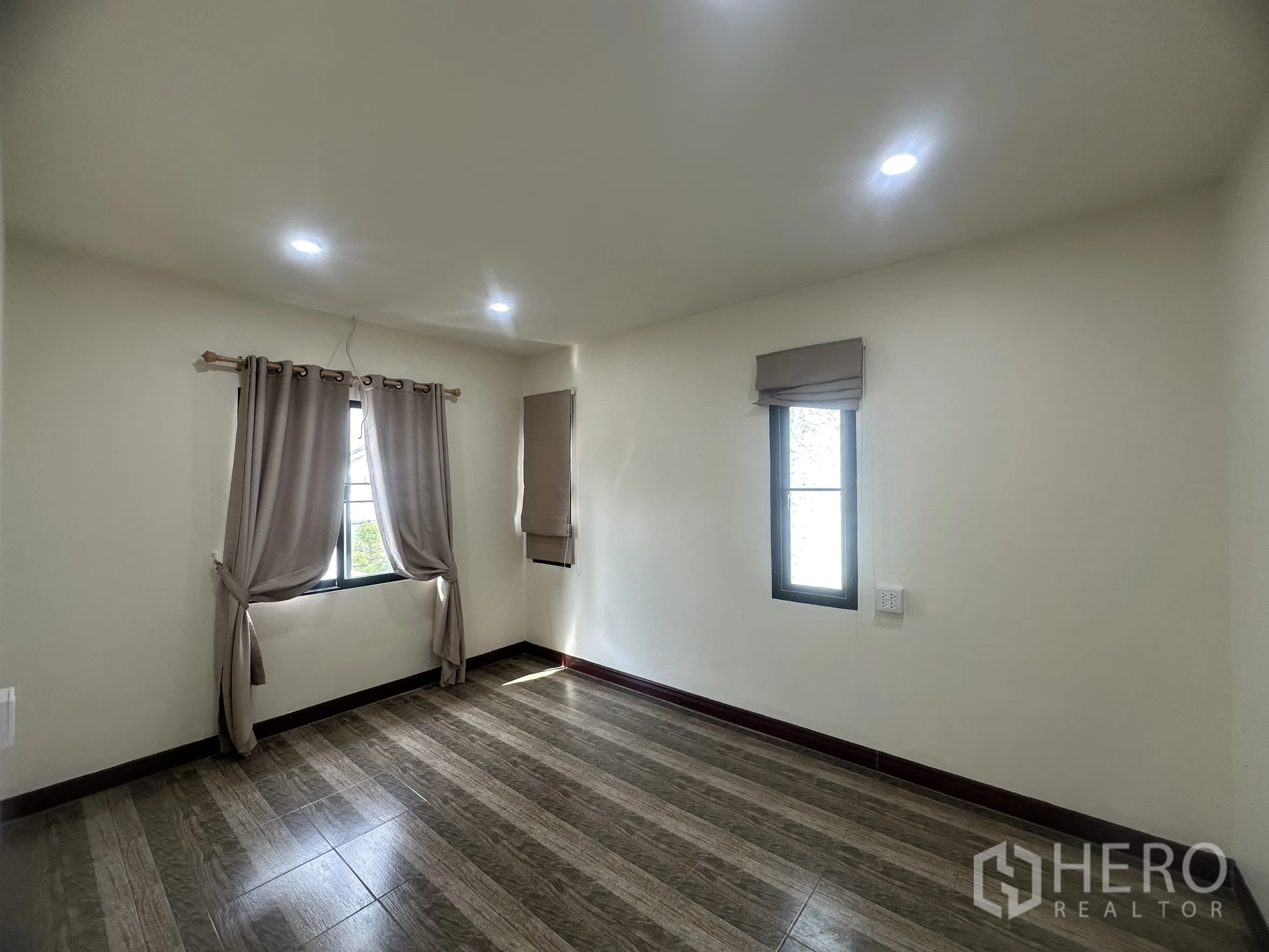 Townhouse for sale in Lam Luk Ka, Pathum Thani - Larger bedroom with multiple windows and curtains.