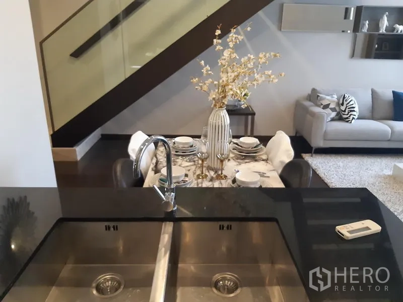 Condominium for rent in Watthana, Bangkok - View from the kitchen island with double sink toward the dining area and sofa.