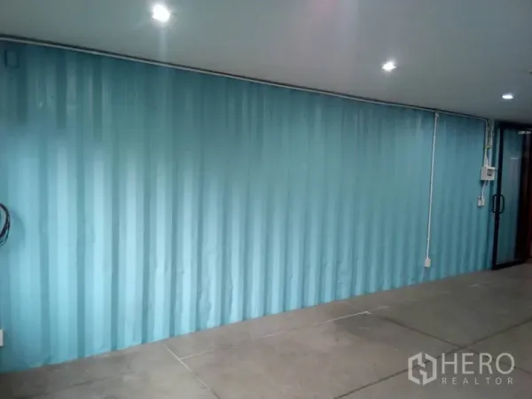 Retail Space for rent in Khlong Toei, Bangkok - Bright retail room with blue corrugated wall and glass door entry.
