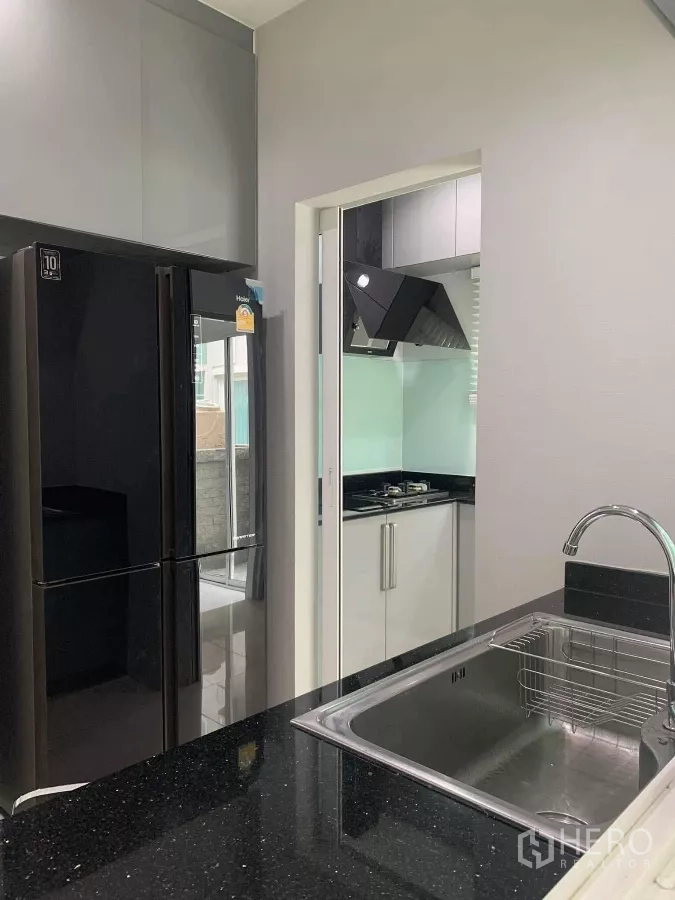 Detached House for rent in Bang Khen, Bangkok - Western pantry with sink and black granite counters overlooking the Thai kitchen.