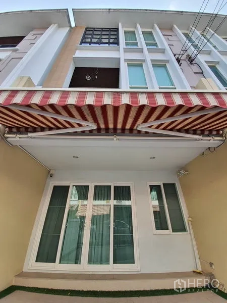 联排别墅 出租在Wang Thonglang, Bangkok - 三层联排别墅外立面，条纹遮阳篷与落地推拉门。