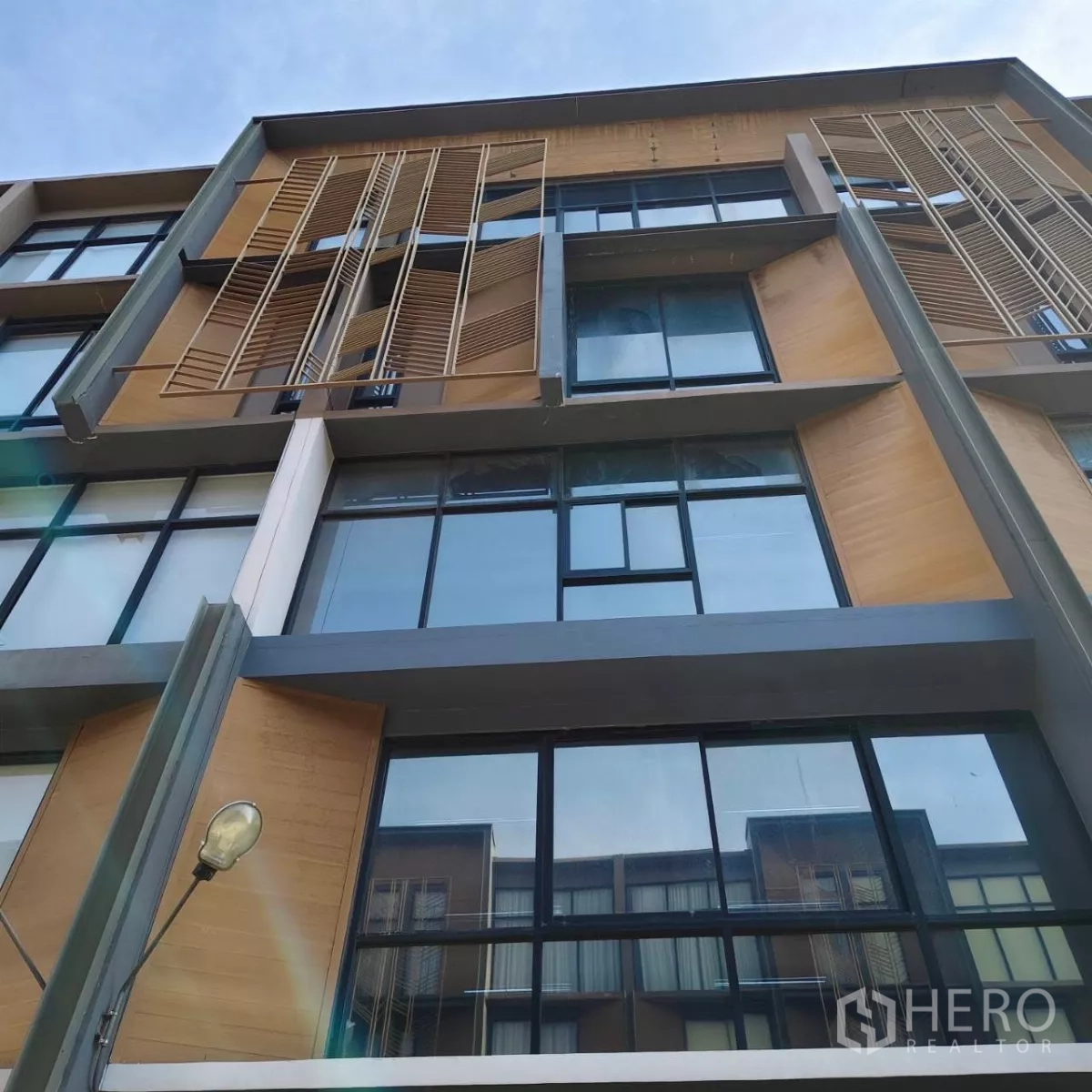 带办公室的家 出租或出售在Watthana, Bangkok - 多层家庭式办公楼外立面，大面积玻璃窗与木质百叶。