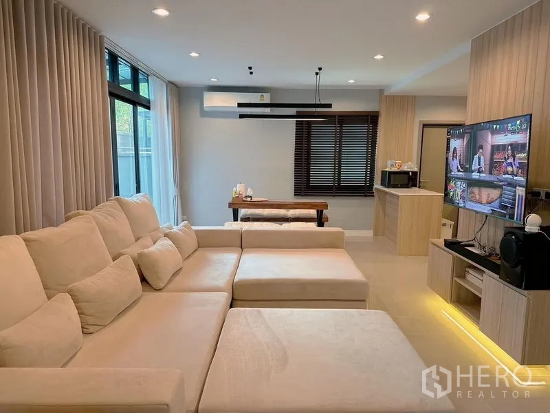 บ้าน ขาย - ห้องนั่งเล่นมีผนังทีวีบิวท์อิน ไฟดาวน์ไลต์ และโซฟาขนาดใหญ่