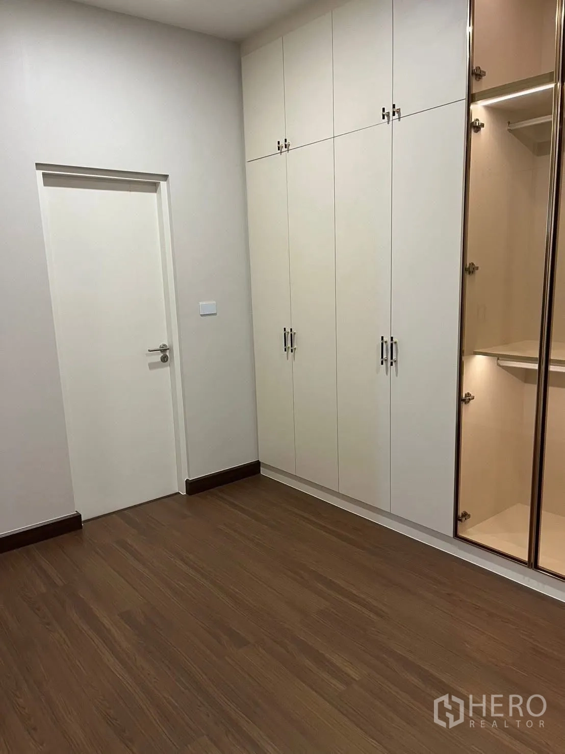 Detached House for rent in Bang Phli, Samut Prakan - Bedroom corner with door and tall white wardrobes on wood floor.