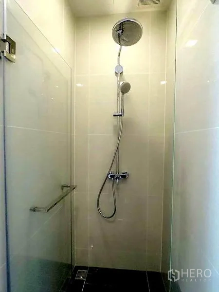 Condominium for rent in Khlong Toei, Bangkok - Tiled bathroom with glass shower enclosure and rainfall showerhead.