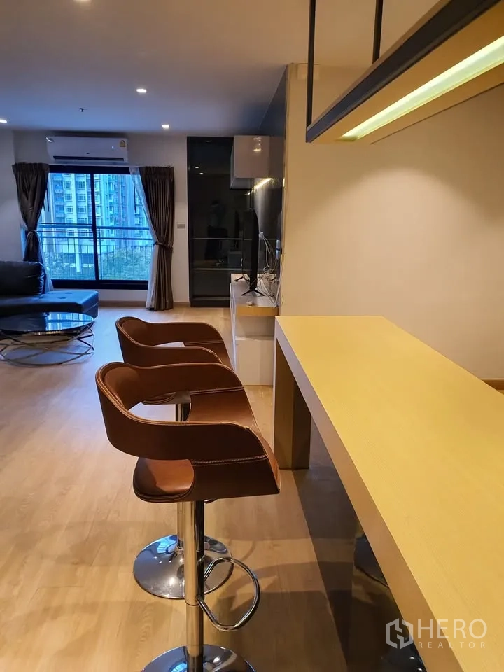 Condominium for rent in Watthana, Bangkok - Breakfast bar with two leather stools beside the living area and large windows.