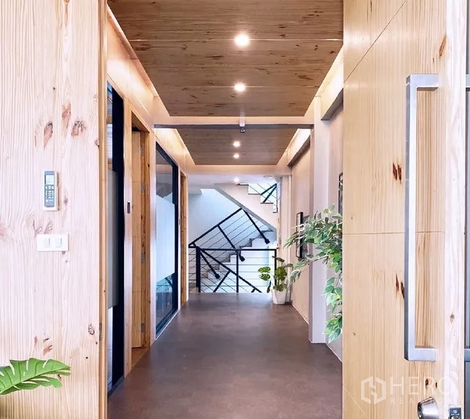 Office Space for rent in Bang Rak, Bangkok - Hallway with wood ceiling panels, large doors, and plants leading toward the stairwell.