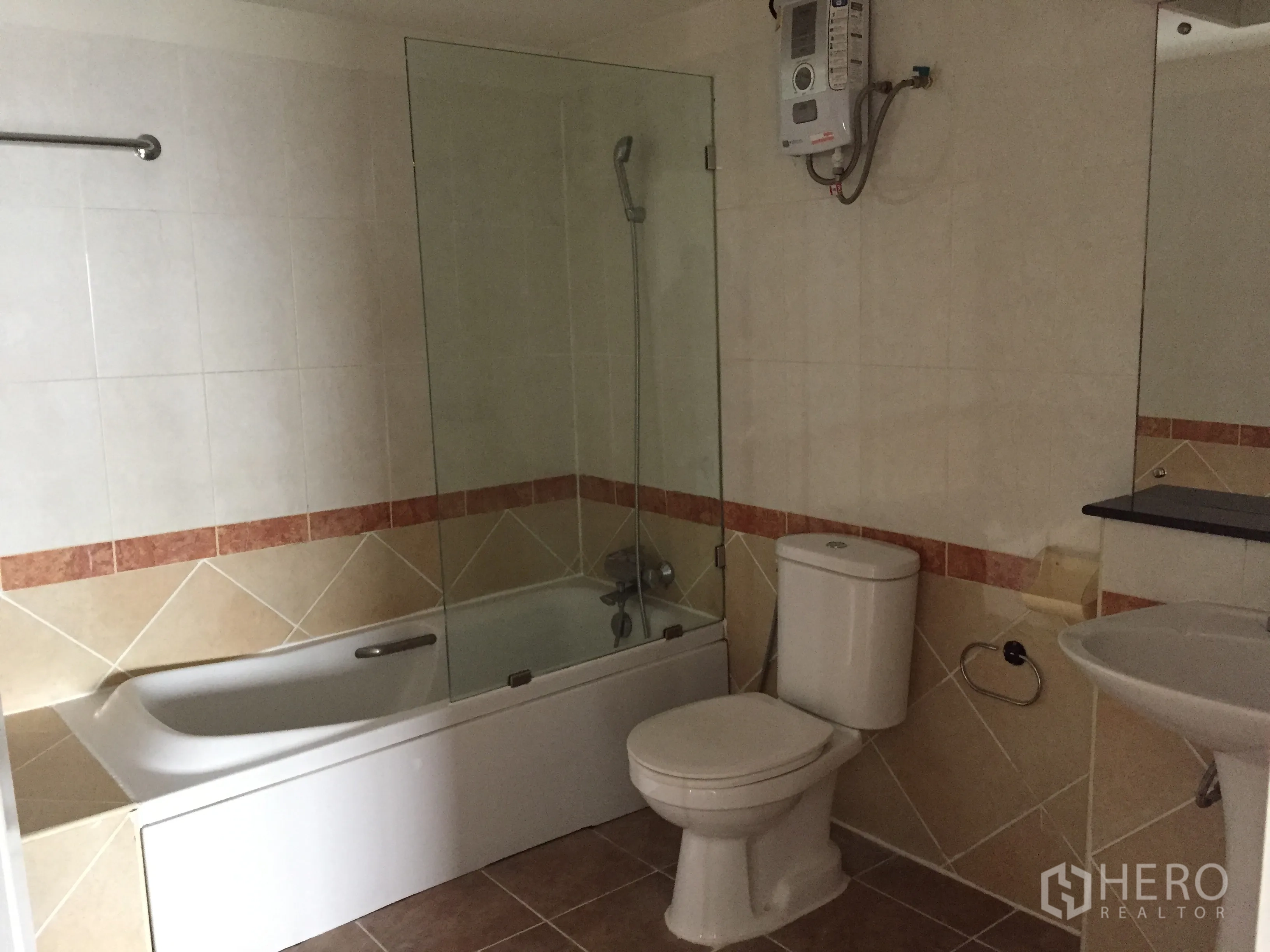 Condominium for rent in Khlong Toei, Bangkok - Bathroom with bathtub, glass shower screen, toilet and sink with water heater.