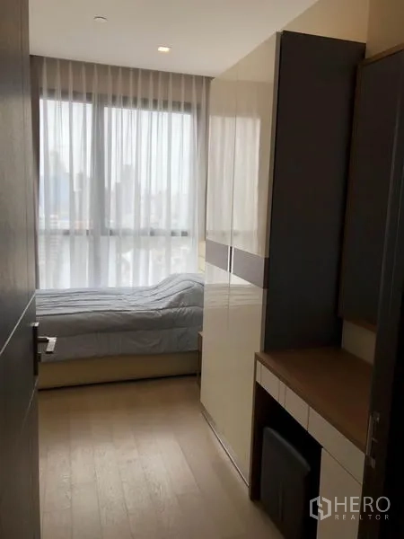Condominium for rent in Watthana, Bangkok - Second bedroom with single bed, built-in wardrobe, dressing desk and city view through large windows.