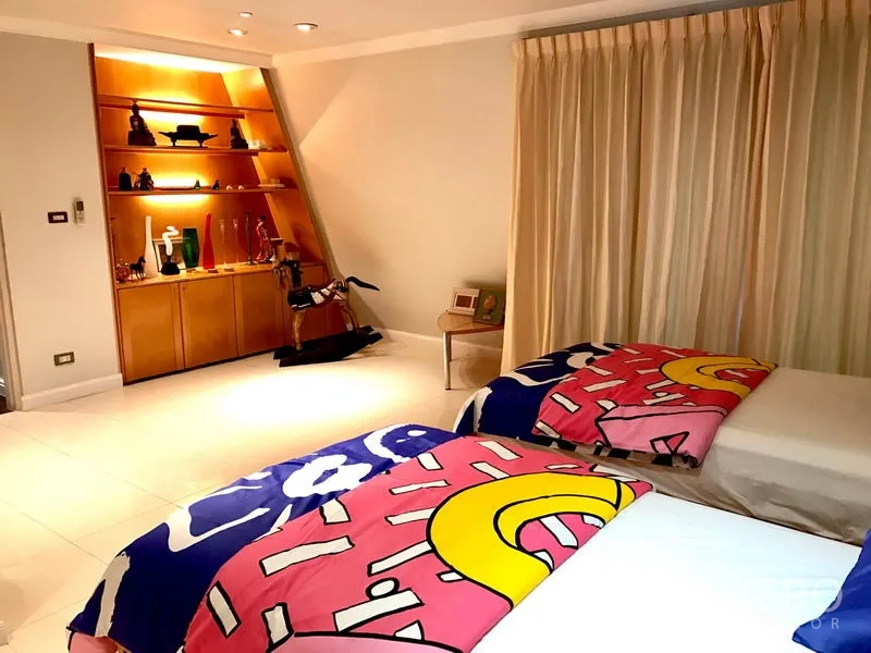 Condominium for rent in Bang Rak, Bangkok - Guest bedroom with two single beds, floor-to-ceiling curtains and illuminated shelving.