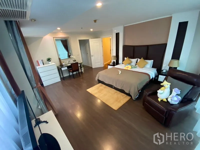 Apartment for rent in Watthana, Bangkok - Master bedroom from another angle with a work desk and recliner beside the bed.
