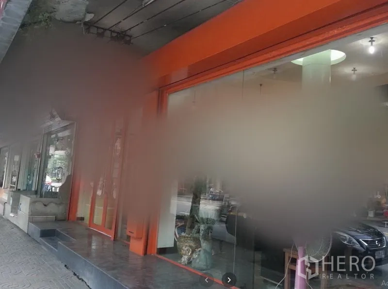 店屋 出租在Watthana, Bangkok - 临街店屋外立面，橙色门框与整面玻璃门面，台阶与带雨棚的人行道。