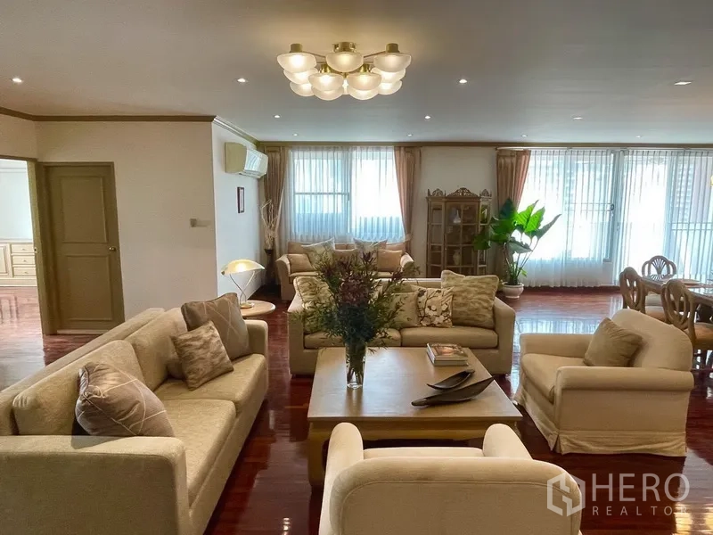 公寓 出租或出售在Watthana, Bangkok - 明亮起居室，多个沙发区与吊顶灯，纱帘覆盖的大窗户。
