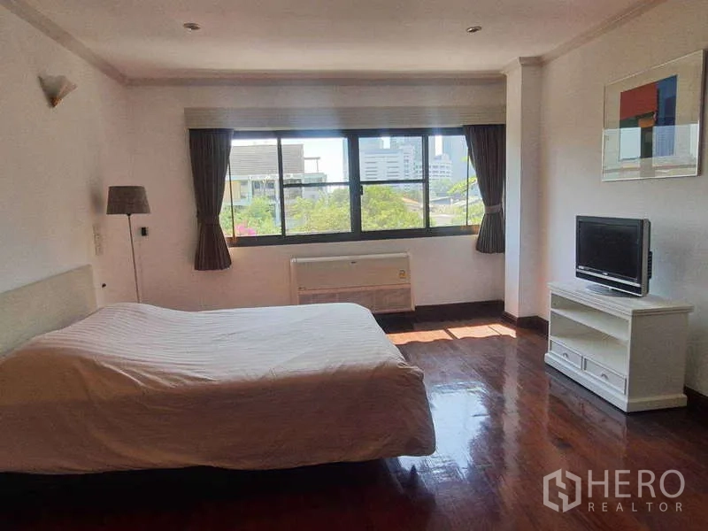 Townhouse for rent in Khlong Toei, Bangkok - Guest bedroom with large window, curtains and TV stand.